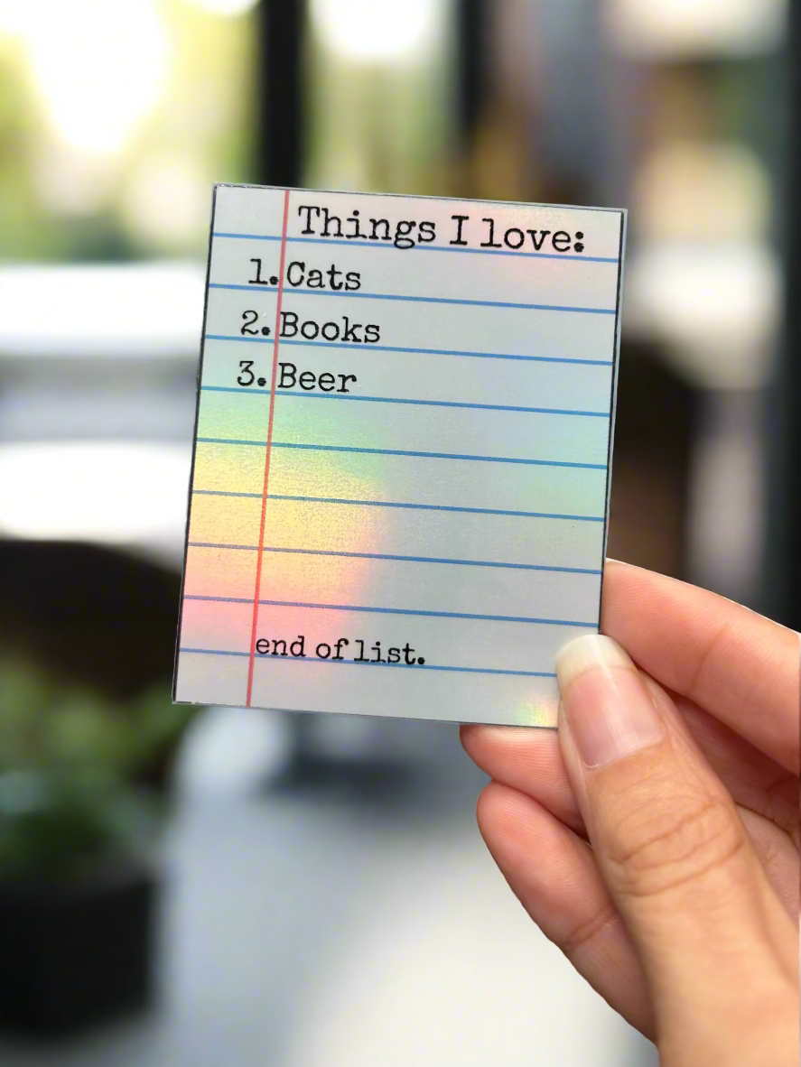 Hand holding a sticker with 'Things I love' list in a coffee shop