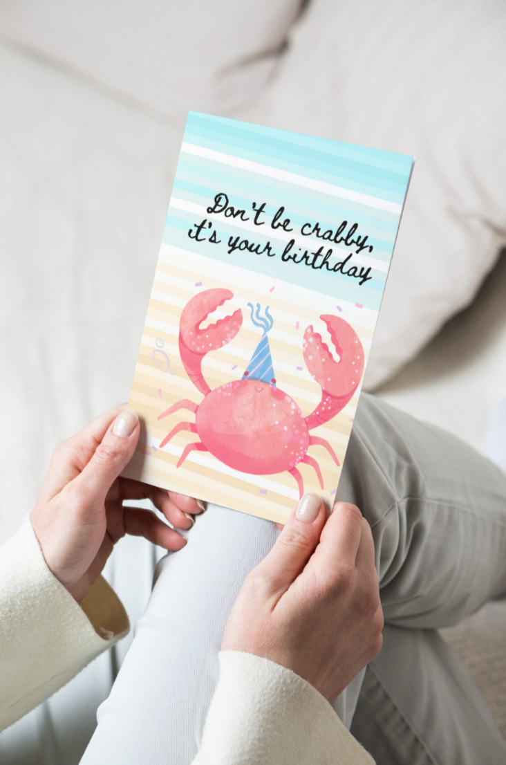 greeting card with an abstract sea background and a crab wearing a birthday hat and text that says don't be crabby, it's your birthday