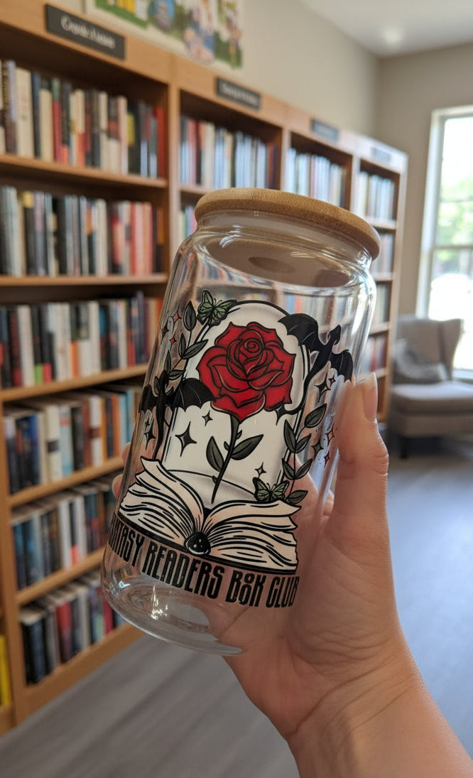 Glass cup with a lid and a rose design and "fantasy readers book club" text held by a hand in a bookstore