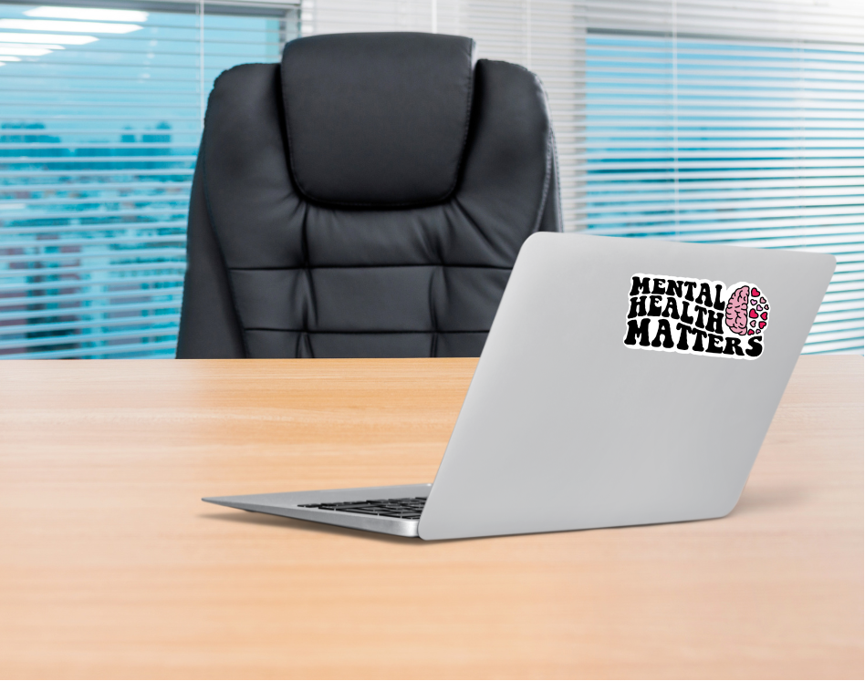 Laptop on a desk with a 'Mental Health Matters' sticker in an office setting