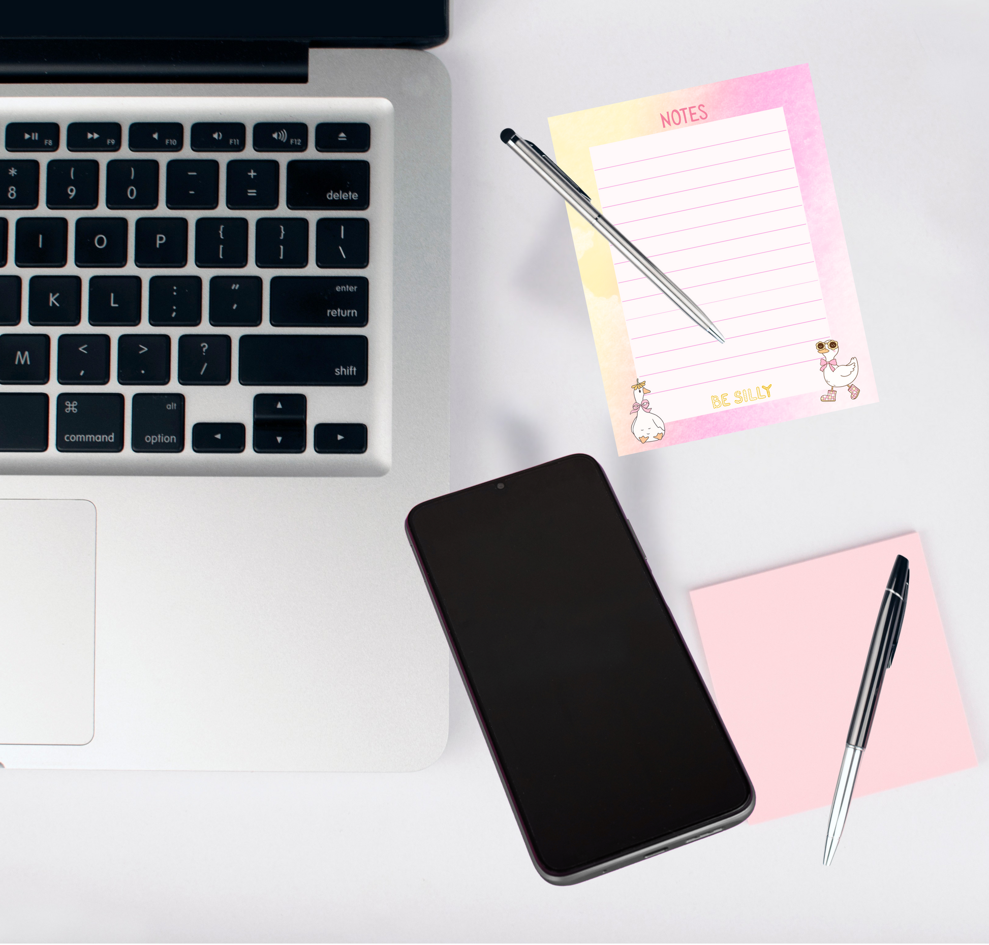 Laptop, smartphone, and stationery items on a white surface