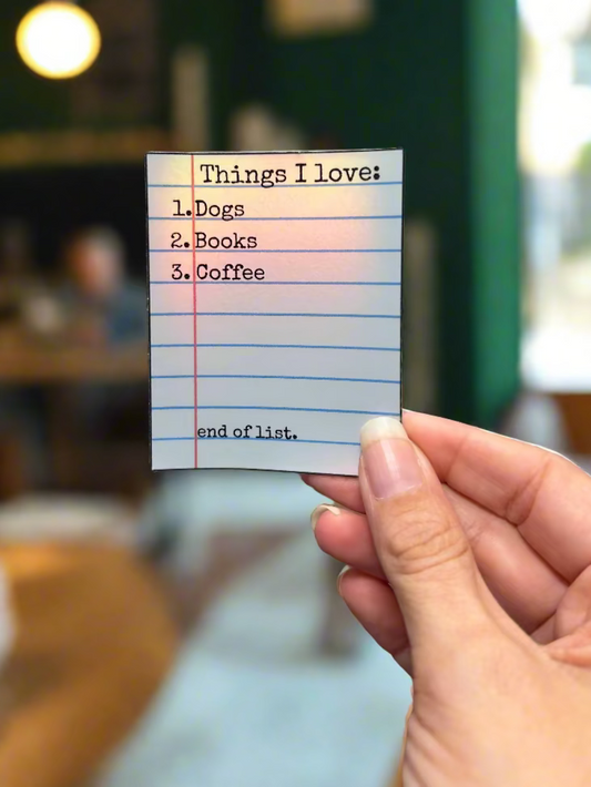 Hand holding a sticker with 'Things I love' list in a coffee shop