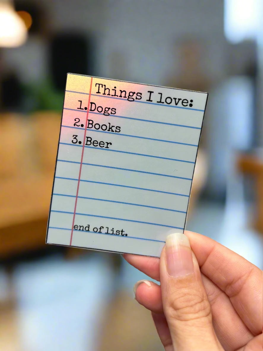 Sticker with 'Things I love' list held by a hand in a coffee shop