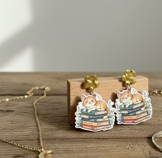 Pair of earrings with cat design on a wooden surface