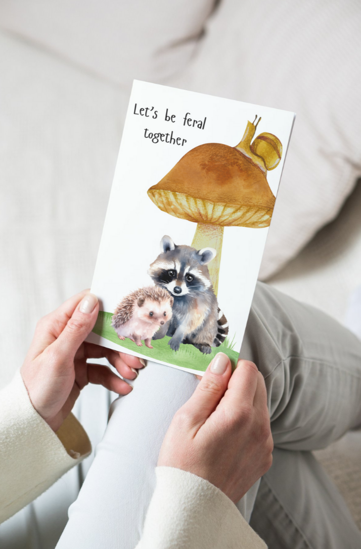 greeting card with a raccoon and hedgehog and the text let's be feral together