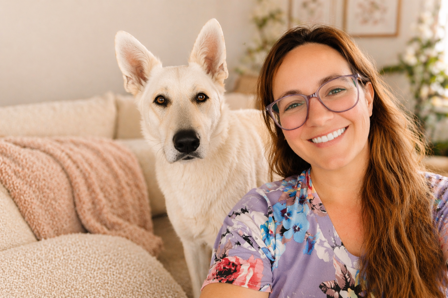 Woman with glasses and a white dog sitting on a couch in a cozy living room.