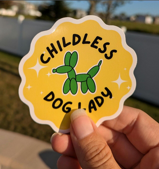Person holding a scalloped yellow sticker with a green dog on it that says Childless dog lady