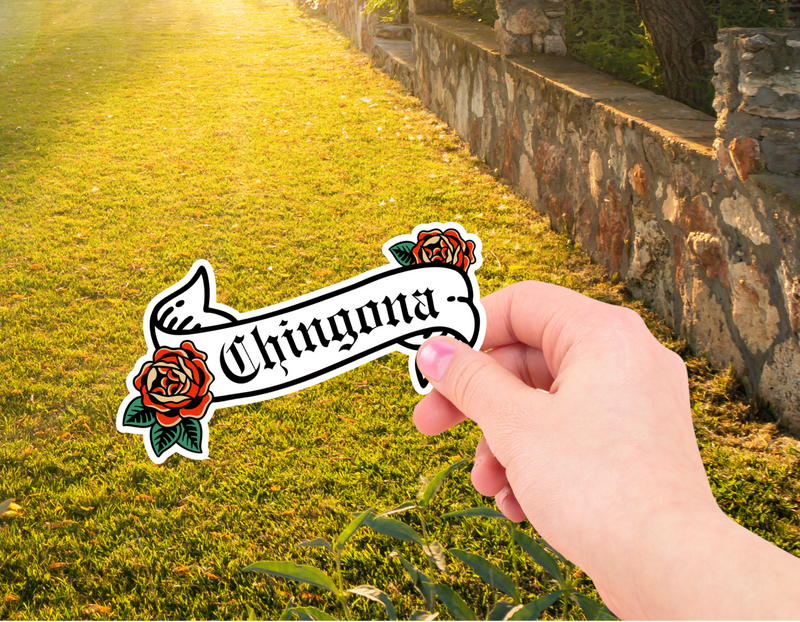 Hand holding a 'Chiugona' sticker with roses against a sunlit garden background
