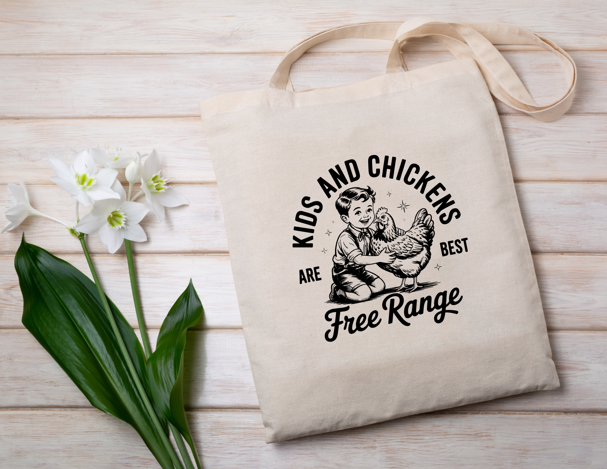 Tote bag with a graphic design featuring "Kids and chickens are best free range" text and an illustration of a child with chickens on a wooden surface with flowers.