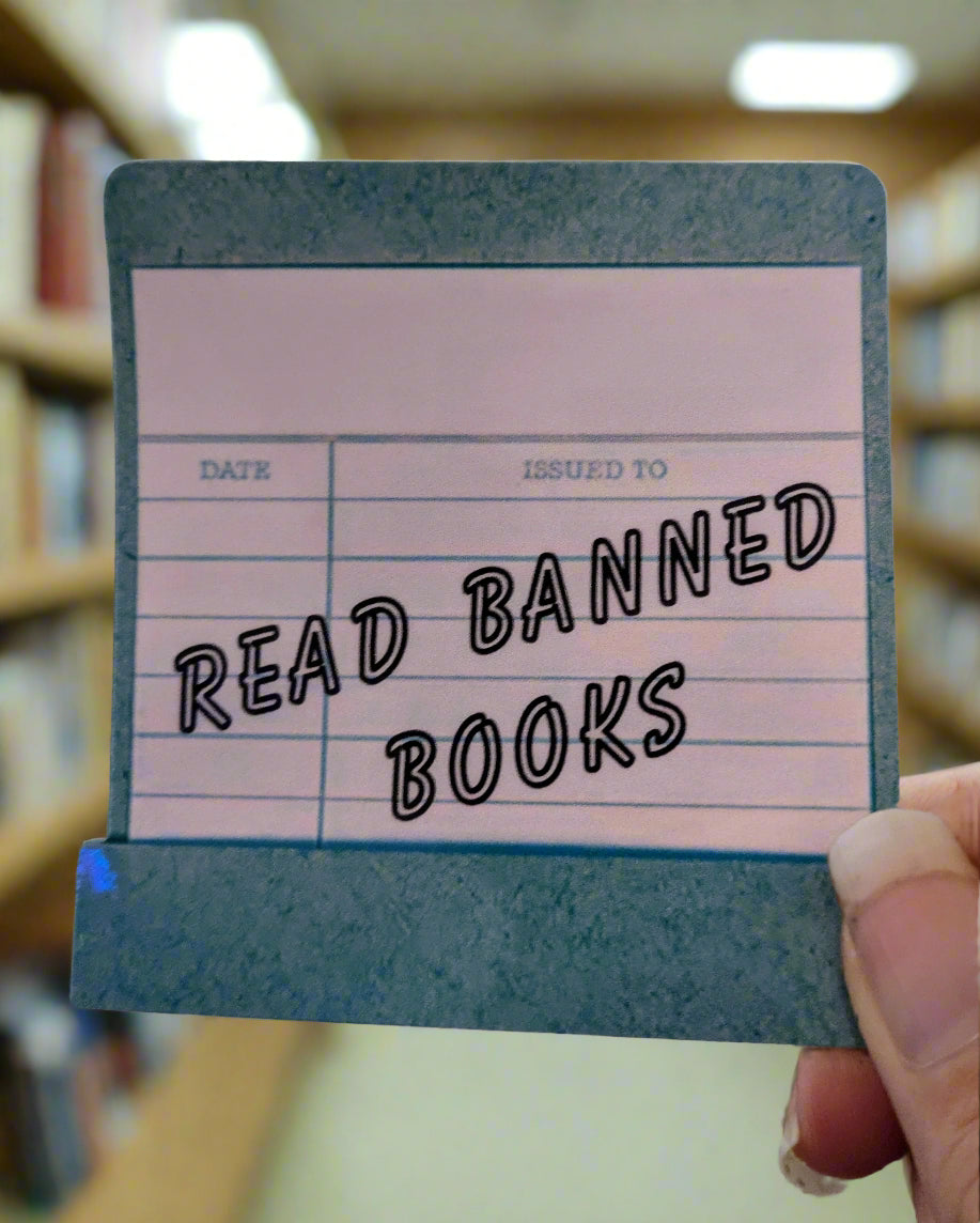 Sticker of a card with 'Read Banned Books' text held by a hand against a blurred background