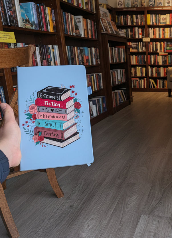 Person holding a blue notebook with a book stack illustration on it in a bookstore