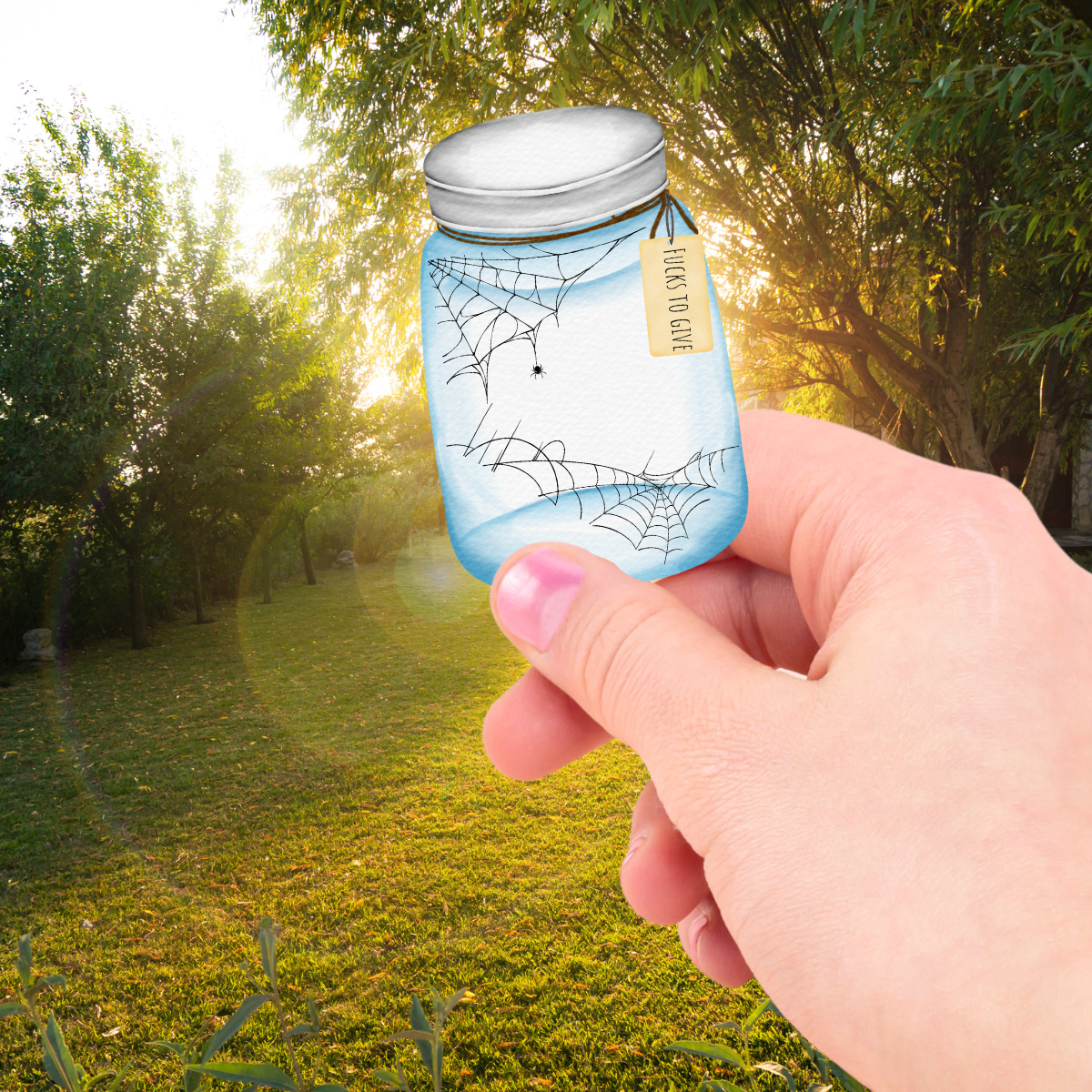 Hand holding a sticker of a small blue jar with spider web design and "fucks to give" against a natural background