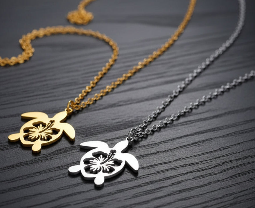Two turtle-shaped pendants on chains against a black background