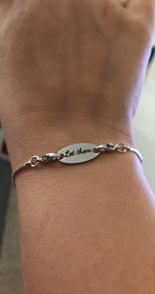 Person wearing bracelet with 'let them' charm on it