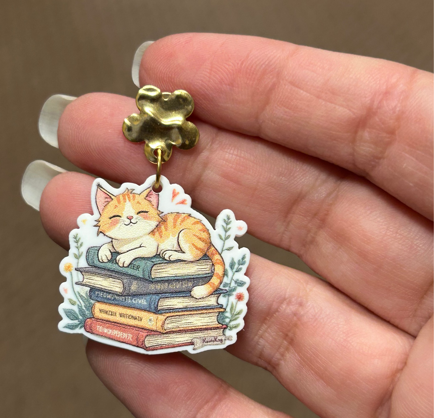 Gold floral stud with a cat laying on books