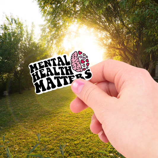 Person holding a sticker with text "mental health matters and a graphic of a brain with hearts