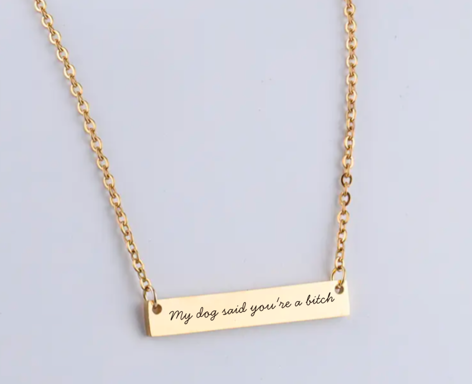 Gold necklace with a bar pendant on a light gray background