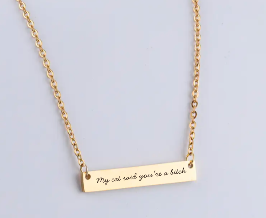 Gold necklace with engraved message on a light gray background