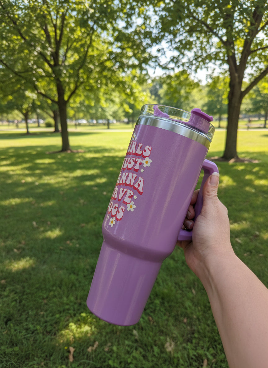 Purple tumbler with text held in a hand against a park background