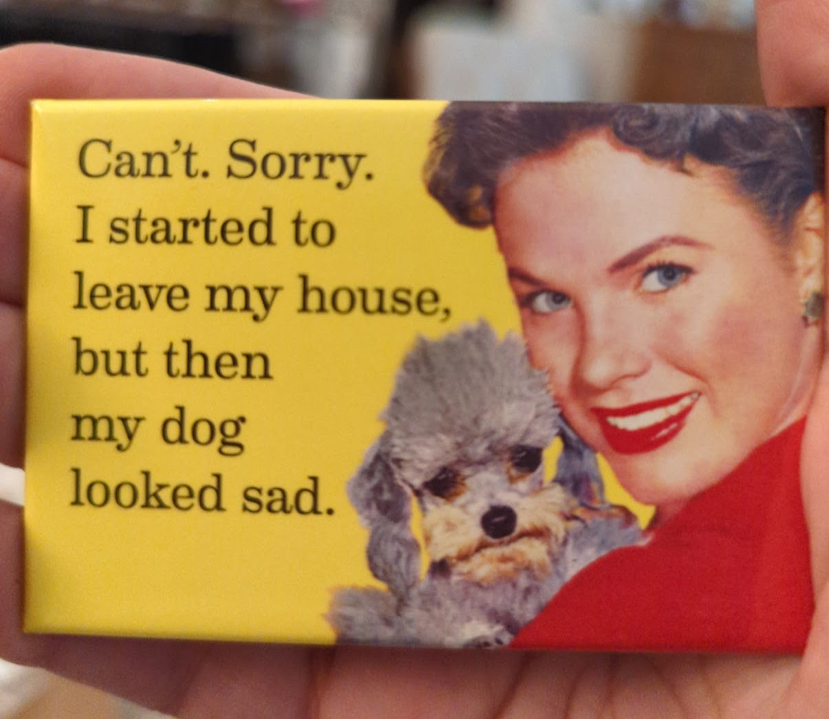 Magnet with text and dog illustration held by a person