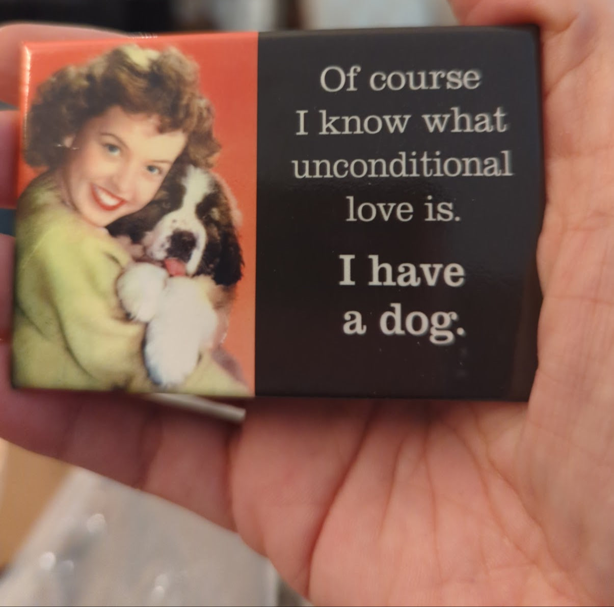 Rectangular magnet with a picture of a woman holding a dog and text about unconditional love.